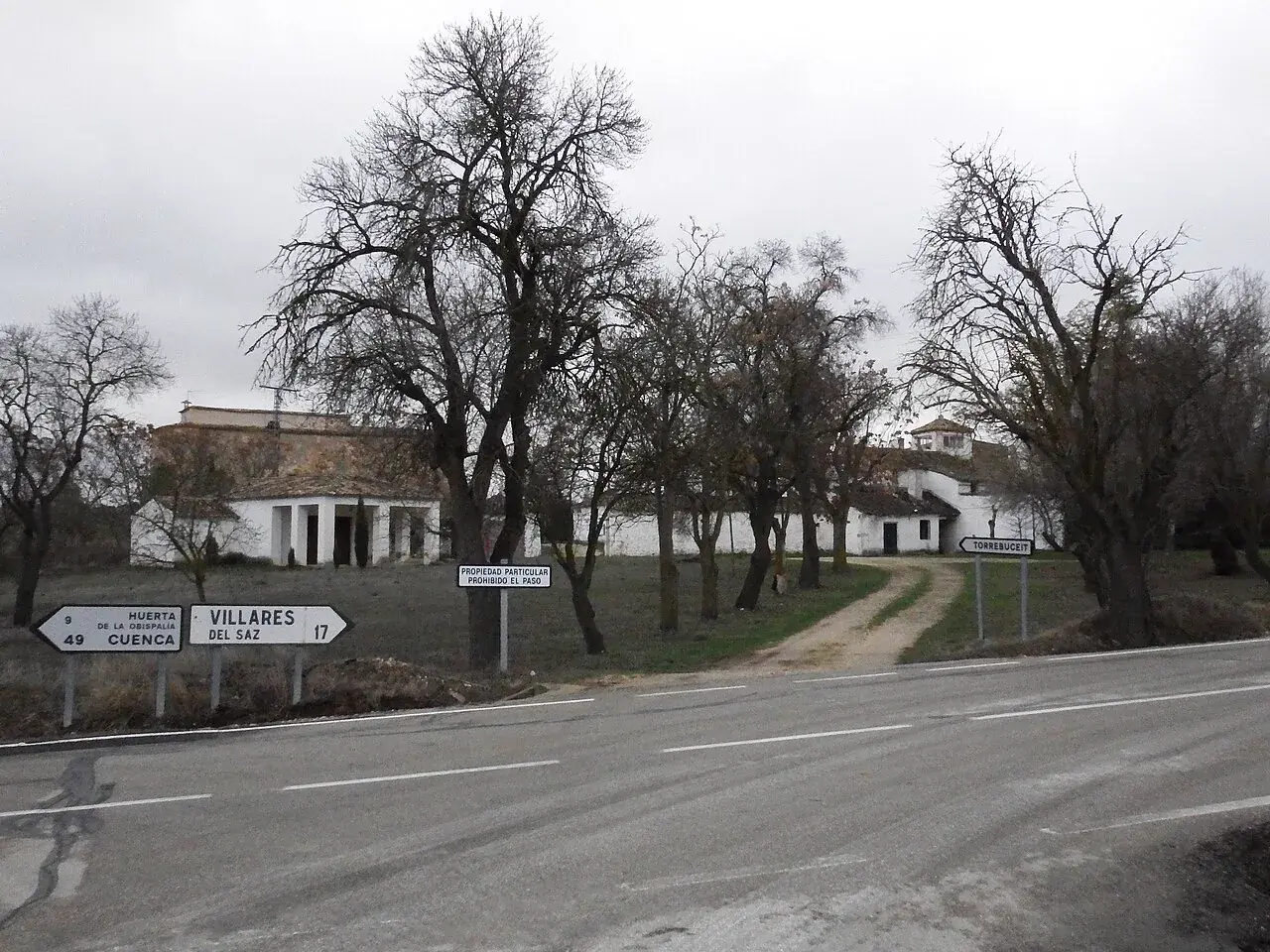 Vista general de Torrebuceit desde la carretera, con el caserío y una señal de propiedad privada